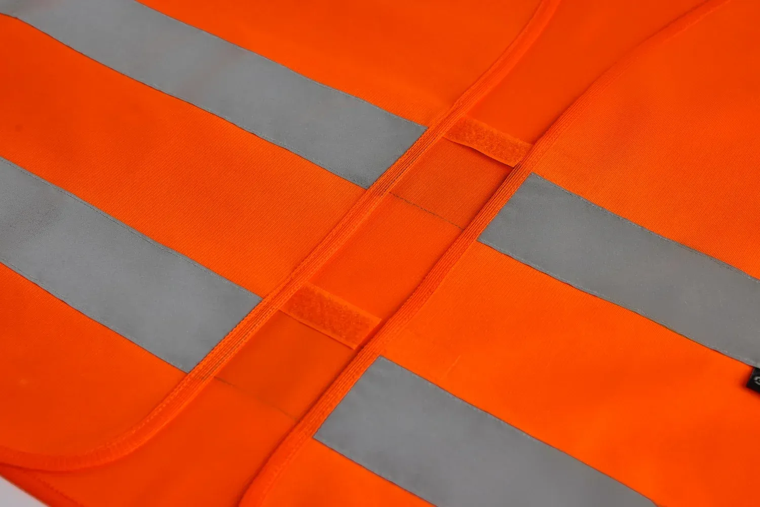 Fluorescent hi-vis garment inspected at roll stage, showing the fluorescent background fabric and retroreflective tape before cutting