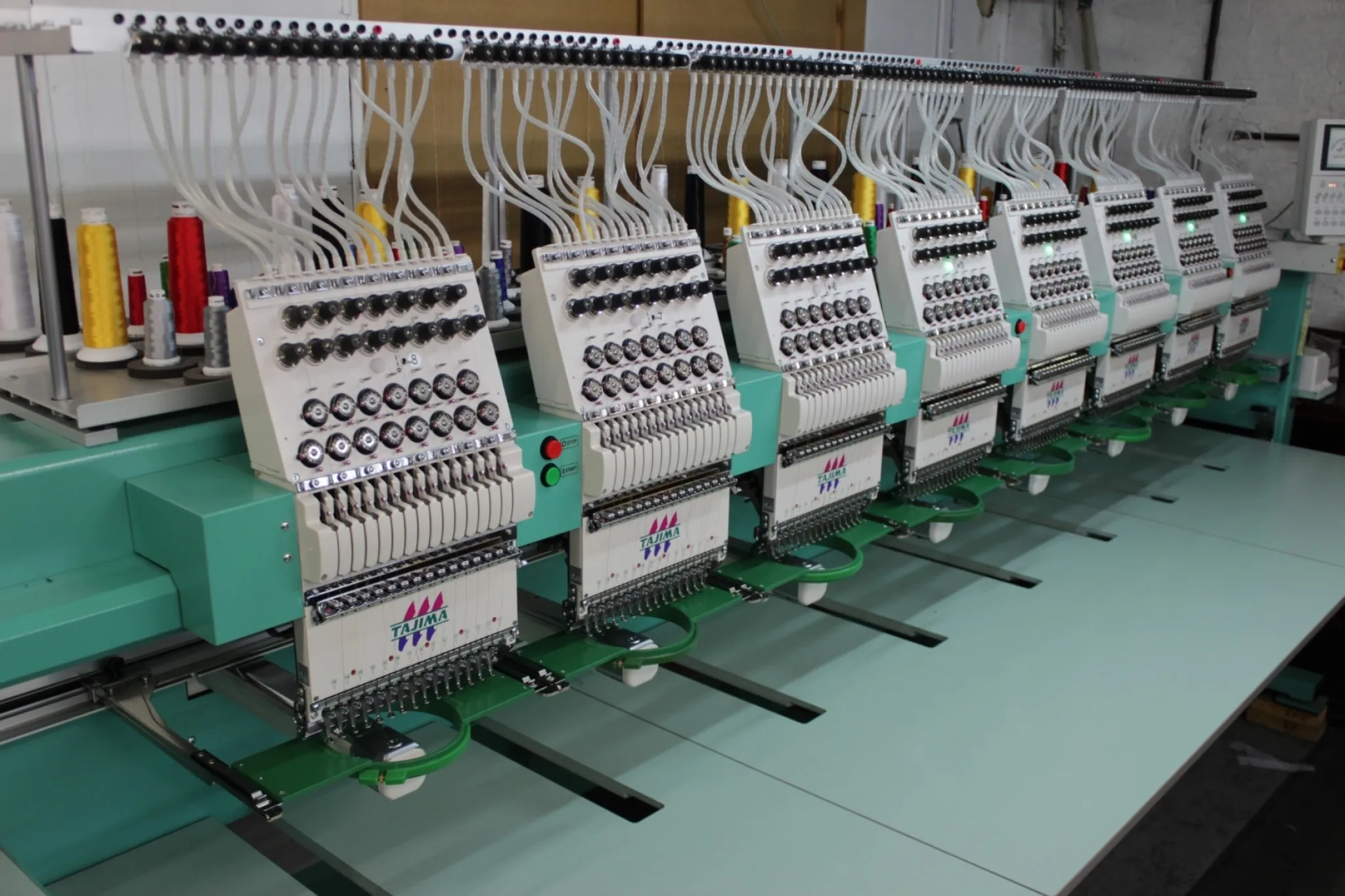 Custom workwear production time: multi-head Tajima embroidery machines running logo application on the factory floor