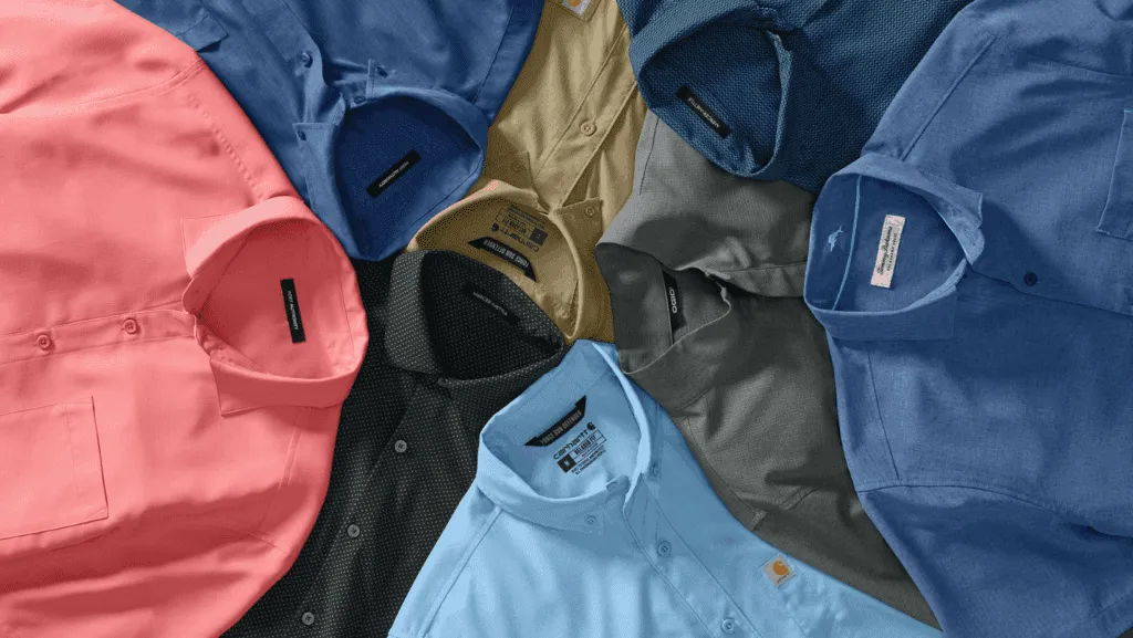 Overlapping work shirts in coral, navy, khaki, black, grey, and blue showing how a wide colorway spread splits a single MOQ into smaller runs