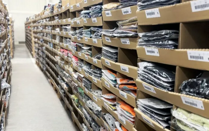 Warehouse shelving stacked with boxed workwear inventory ready for multi-site distribution