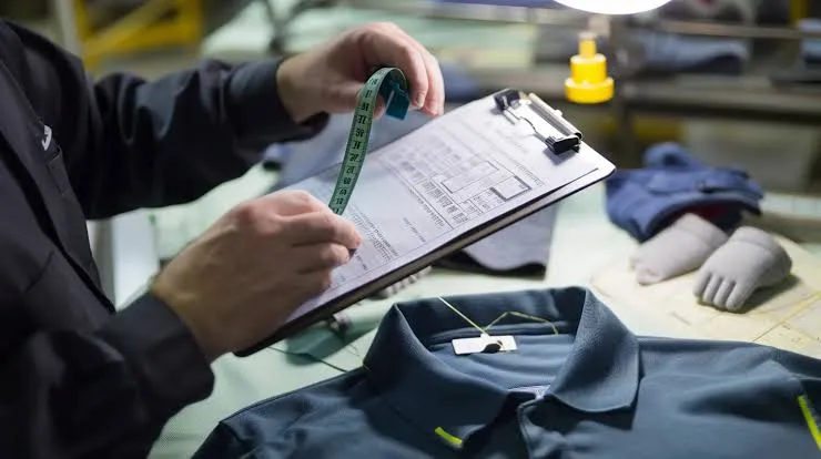 QC inspector measuring a garment against a written inspection sheet
