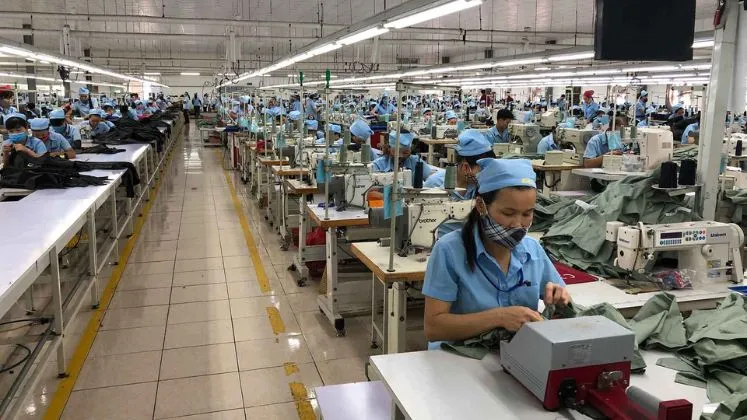 Rows of sewing stations and operators on a workwear factory floor