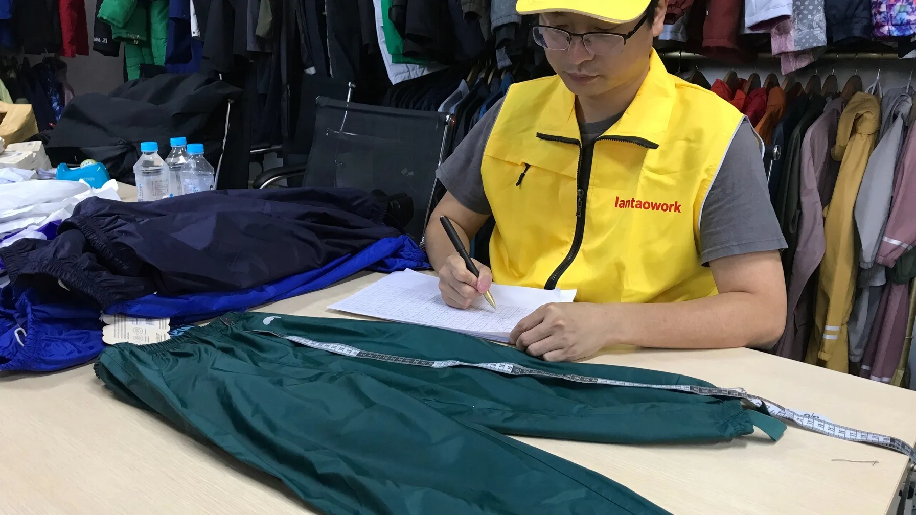 QC check — measuring a sample trouser against the size sheet before release