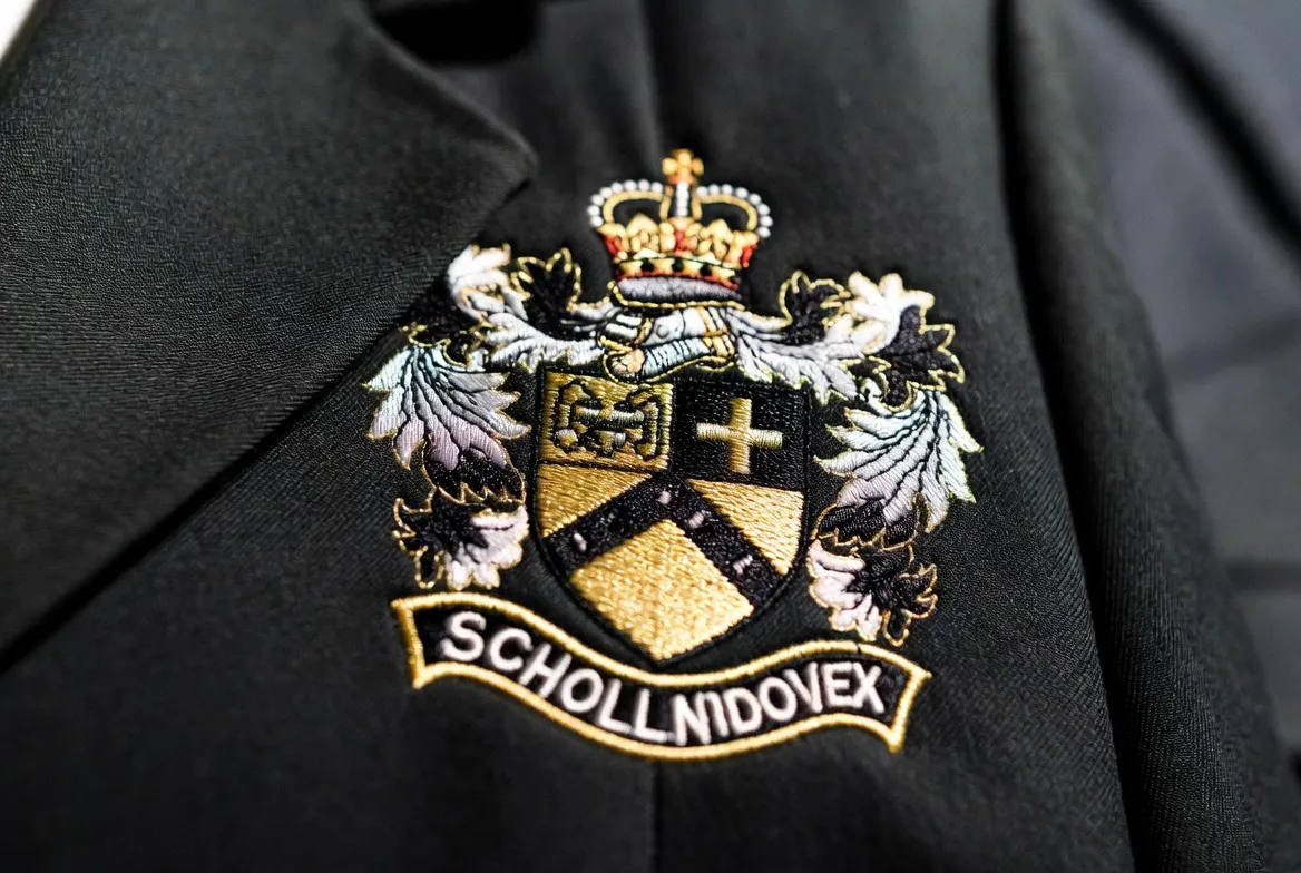 Close-up of detailed multi-color school crest embroidery on uniform blazer fabric